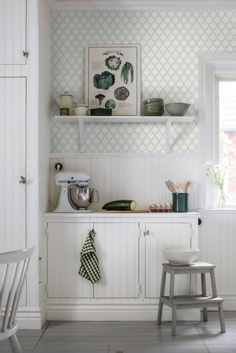 Cocina con pared decorada con papel pintado con motivos de hojas y formas geométricas enrejadas en blanco y verde