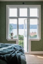 Habitación decorada con papel pintado con motivos de hojas de avellano en verde oscuro