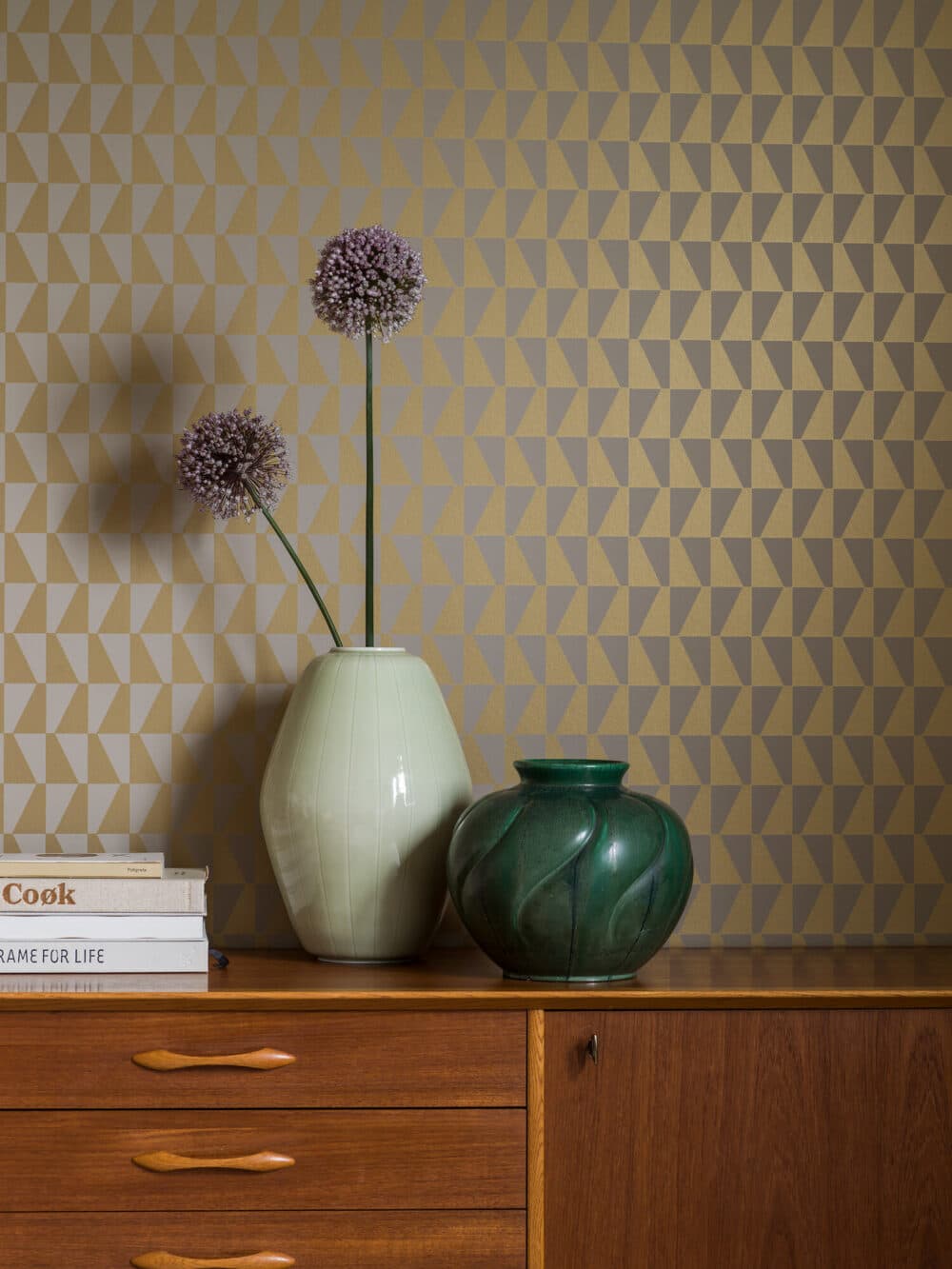 Pared decorada con papel pintado con sofisticados motivos geométricos "Arne Jacobsen Trapez" color dorado