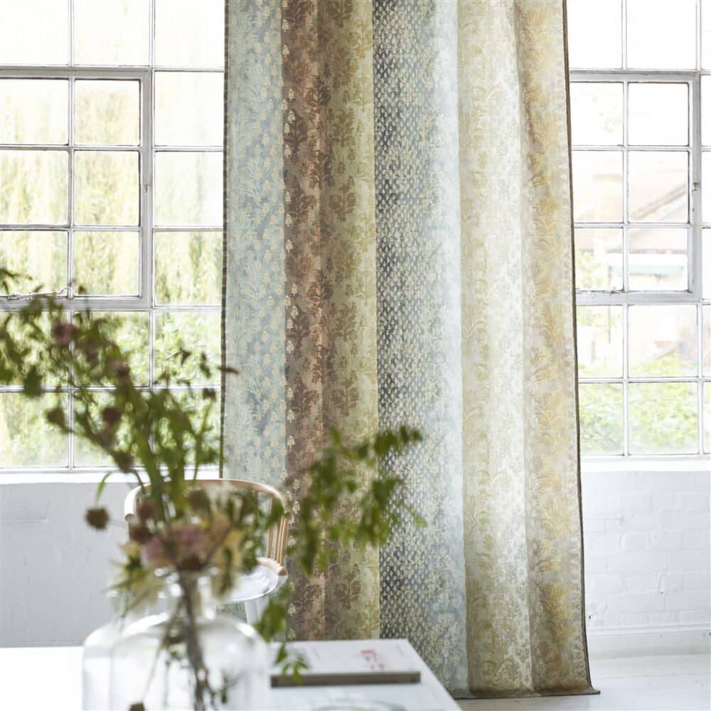 Habitación decorada con cortinas confeccionadas con algodón de estampado tipo sari y motivos dorados en tonos naturales