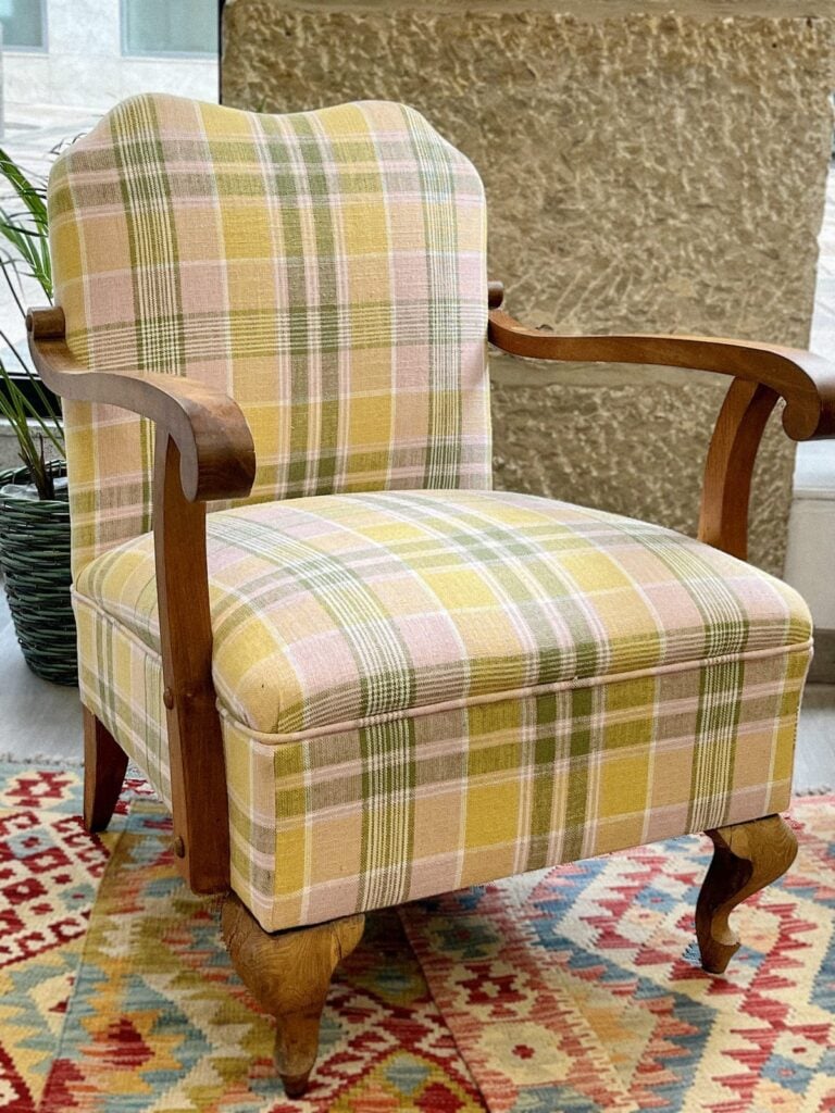 Antieke fauteuil gerestaureerd en opnieuw bekleed met geruite stof.